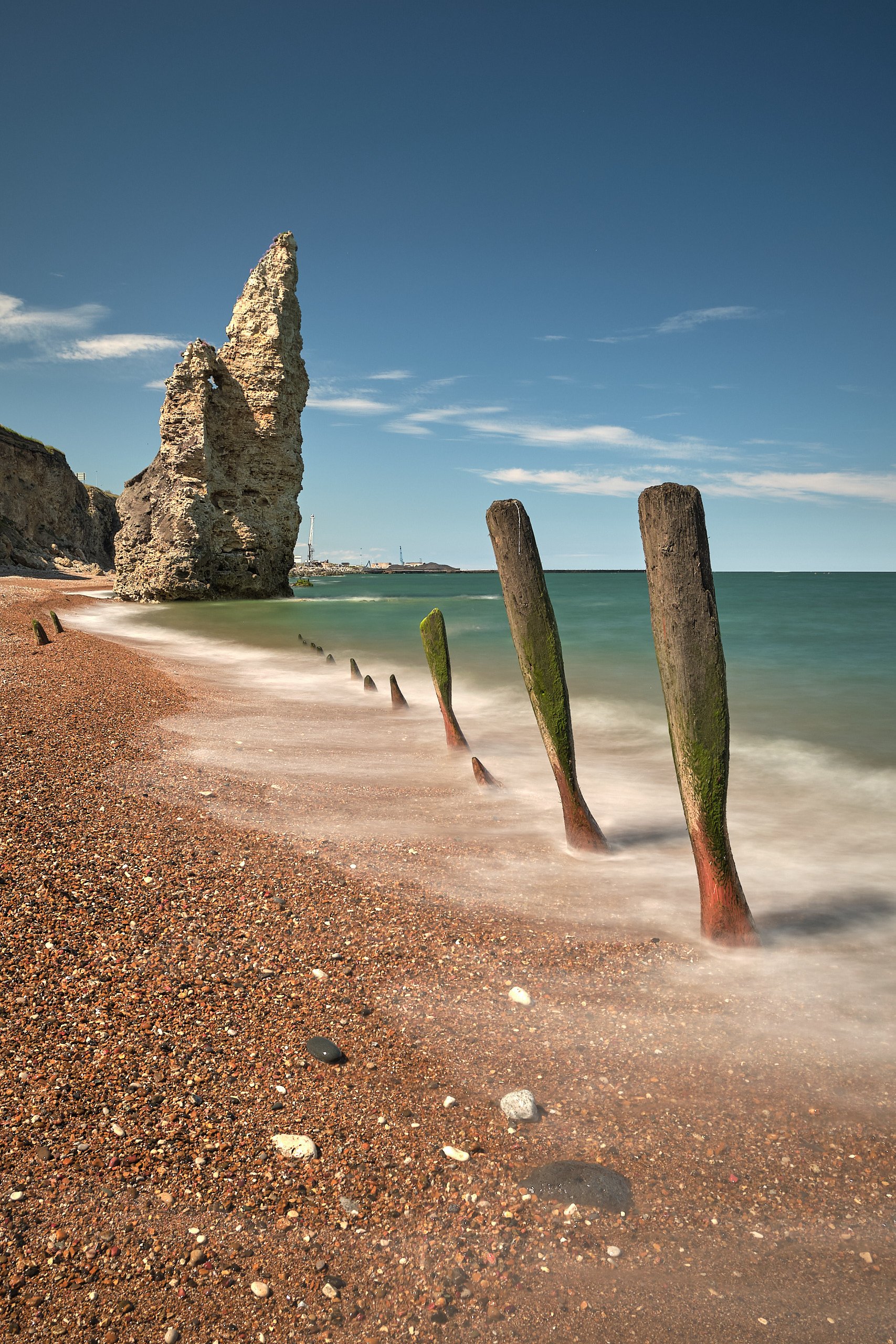 Sea stack and wooden groynes exposed at low tide on Chemical Beach