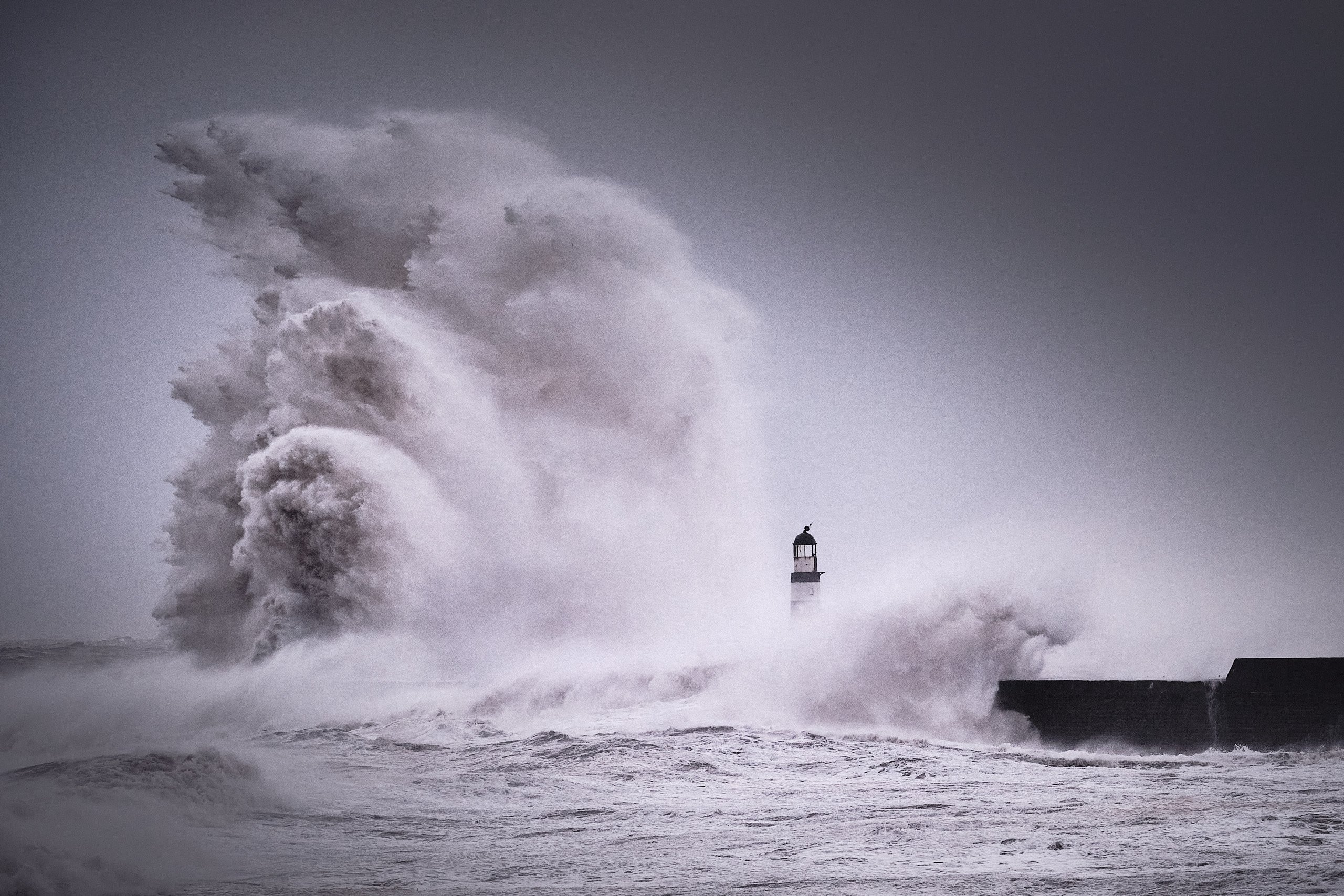 Large storm waves crashing over Seaham Pier and lighthouse during Storm Arwen